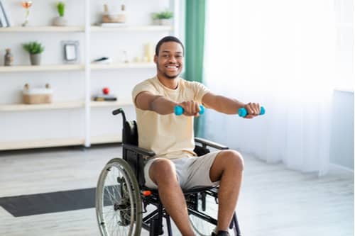Young African American man in wheelchair exercising, Cape Coral spine injury treatment