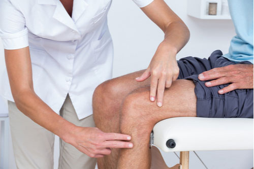 Pompano Beach bursitis treatment physical therapist examines knee