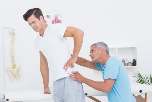 Back injury treatment in Sunrise, chiropractor examines man with back pain
